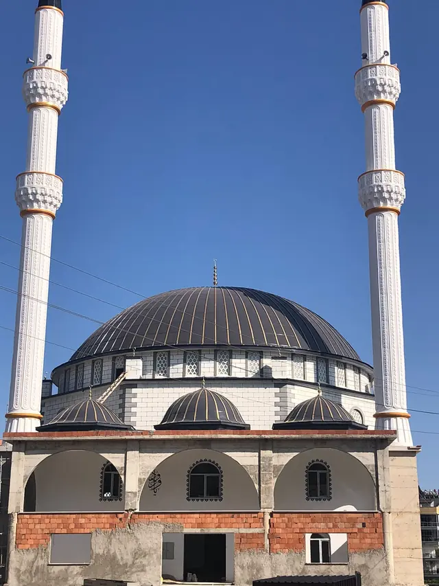 İki minare arasında pirinç renkli kenet hatlarıyla antrasit kaplı ana kubbe ve üç yarım kubbe