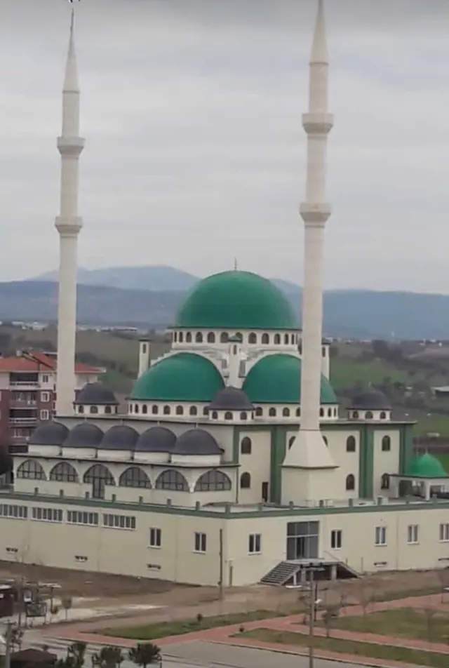 Yeşil kaplı ana kubbe ve yarım kubbeler ile antrasit kubbecikli, çift minareli büyük cami